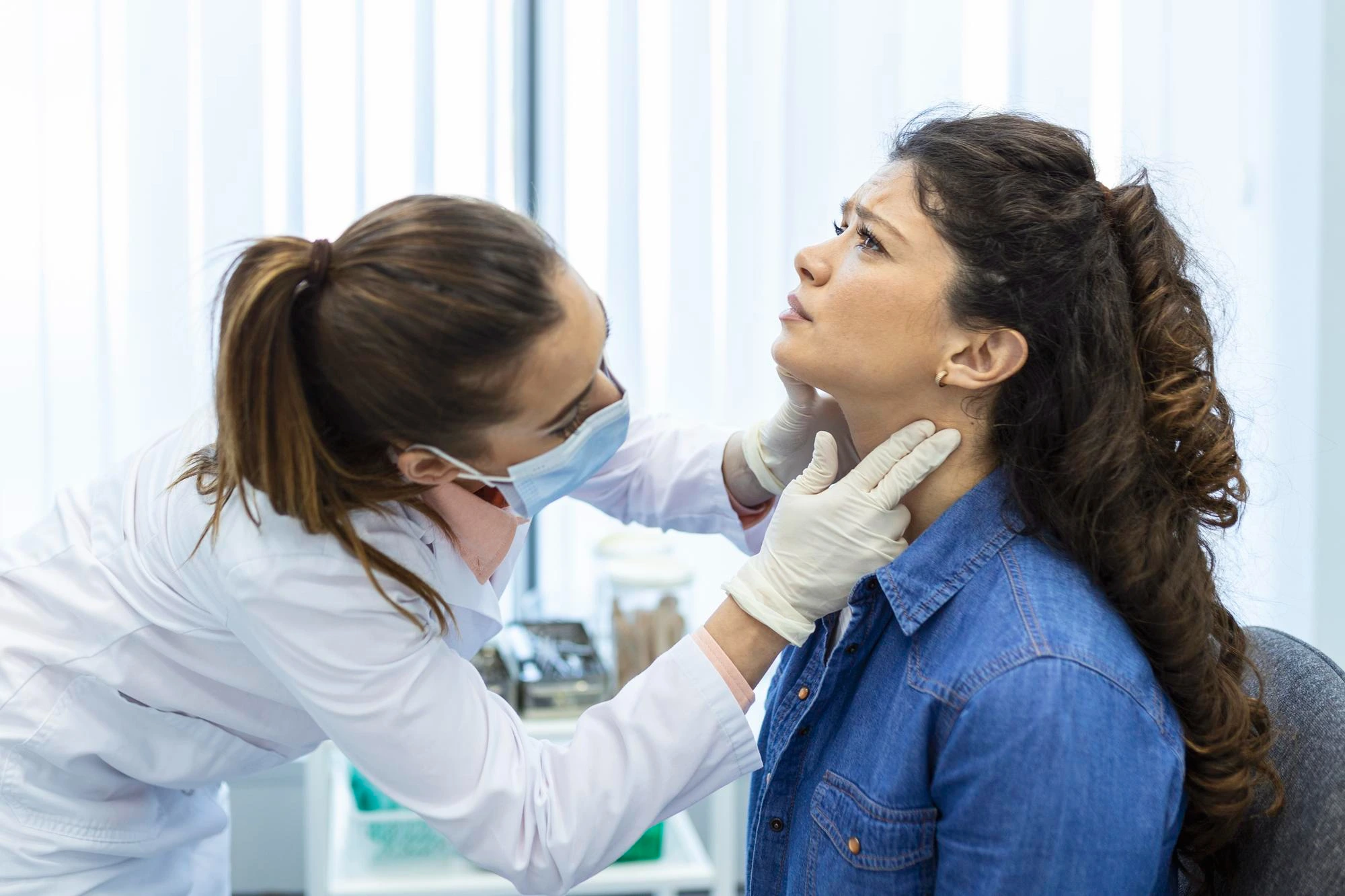 ABOUT US 3 ENT doctor examining a patient's throat during a medical consultation